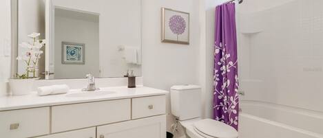 A modern bathroom with a white sink, toilet, and shower area.