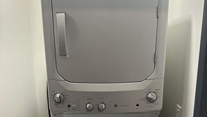 A front-loading washer and dryer in a laundry room with a control panel and a yellow EnergyGuide label. - Luxury King Suite Downtown Kalamazoo (Kalamazoo)