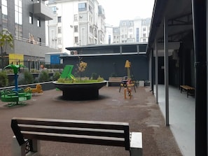 An outdoor area with a playground, benches, and a building in the background. - Black Tower (Tashkent)