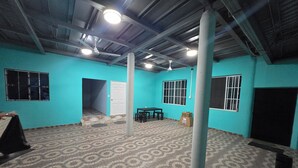 Ein Zimmer mit türkisfarbenen Wänden, einem gemusterten Boden, einem Deckenventilator und einem Tisch mit Stühlen.