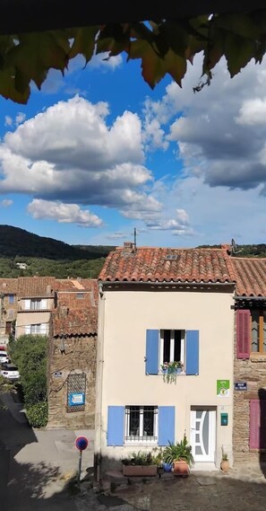 A traditional building with a tiled roof, a window with blue shutters, and a door with a white frame. - BLEU D'OPALE - LA GARDE FREINET (LA GARDE FREINET)