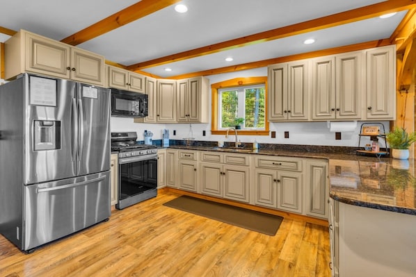 A modern kitchen with wooden cabinets, stainless steel appliances, and a window providing natural light. - Cliffside Cabin, Stunning views and 100% privacy (West Decatur)