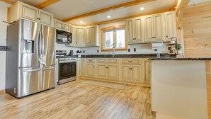 Eine Küche mit Holzausstattung, einem Edelstahlkühlschrank, einem Backofen und einem Spülbecken.