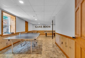 A game room with a ping pong table, a pool table, and a billiards table.