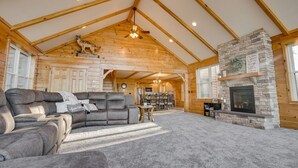 Ein geräumiges Wohnzimmer mit Kamin aus Stein, Holzbalken und einem großen Ecksofa.