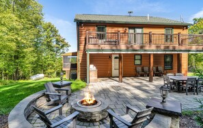 Eine Blockhütte mit Feuerstelle, Sitzgelegenheiten im Freien und einer überdachten Terrasse.