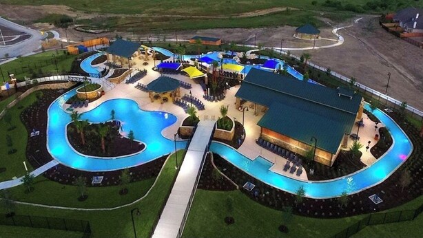 Una gran piscina con diseño sinuoso, rodeada de zonas de descanso y asientos cubiertos.