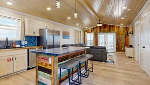 Una cucina moderna con soffitto in legno, sgabelli da bar e un'isola grande.