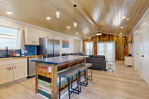 A modern kitchen with wooden ceiling, bar stools, and a large island. - CL6 Shared Pool, Charcoal Grill, Old Town Port A (Port Aransas)