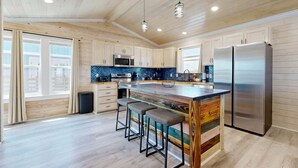 Una cucina moderna con mobili in legno, una grande isola con sgabelli, elettrodomestici in acciaio inossidabile e vista sulla città.
