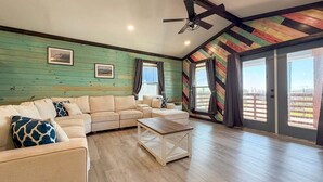 A spacious living room with a sectional sofa, a coffee table, and a ceiling fan. - CL7 Shared Pool, Charcoal Grill, Old Town Port A (Port Aransas)