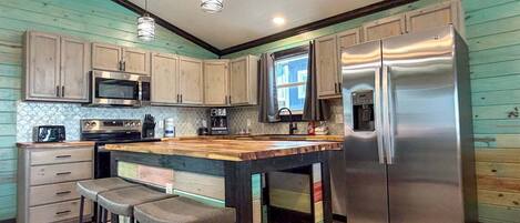 A kitchen with wooden cabinets, a stainless steel refrigerator, a microwave, and a coffee maker.