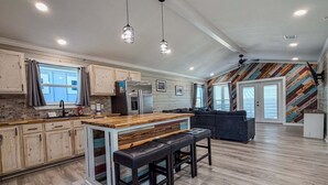 Une cuisine spacieuse dotée d’un îlot central, de meubles en bois et d’un réfrigérateur moderne.