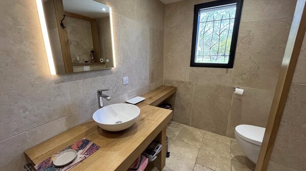 A modern bathroom with a large sink, mirror, and window.