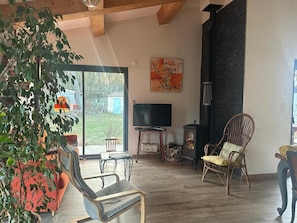 A living room with a large window, a television, a fireplace, and a dining area.