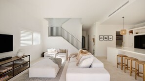 A modern living room with a white sofa, a TV, and a staircase. - Casa Bianca, Bondi IH (Bondi)