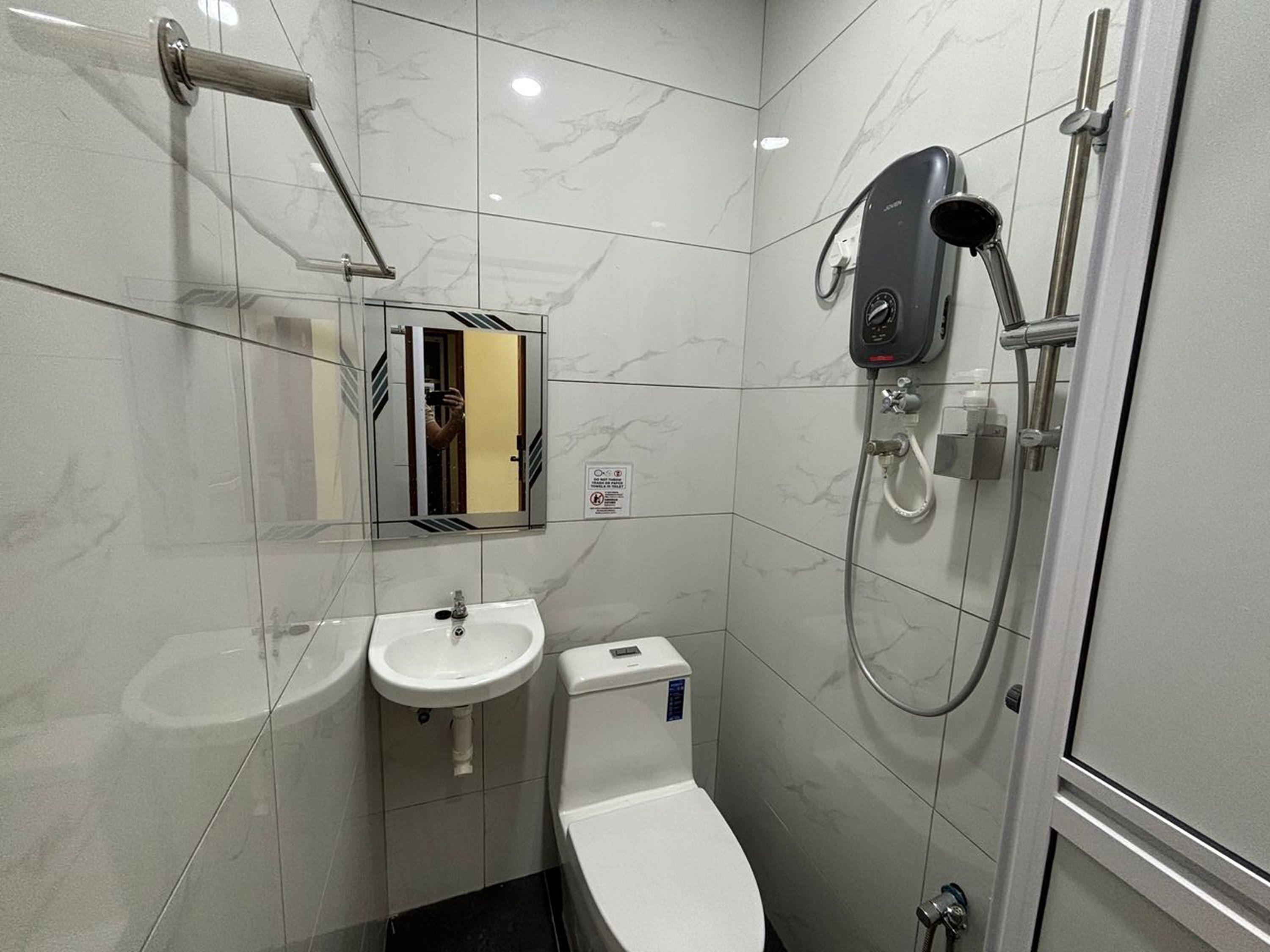Casa de banho compacta com sanita, lavatório e chuveiro.