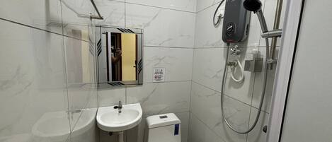 Un baño pequeño con inodoro, lavamanos y ducha.