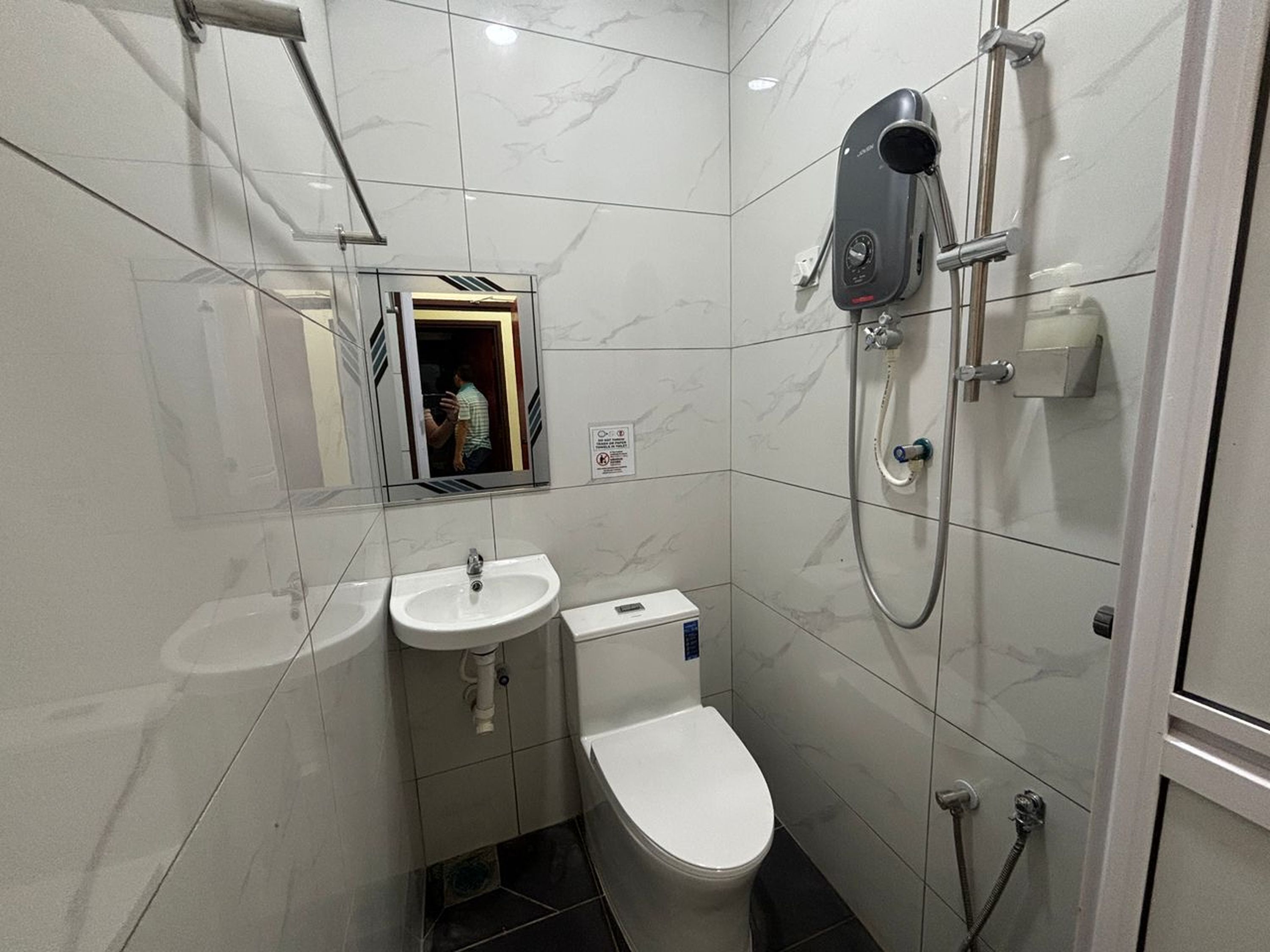 A compact bathroom with a toilet, two sinks, a shower, and a mirror.