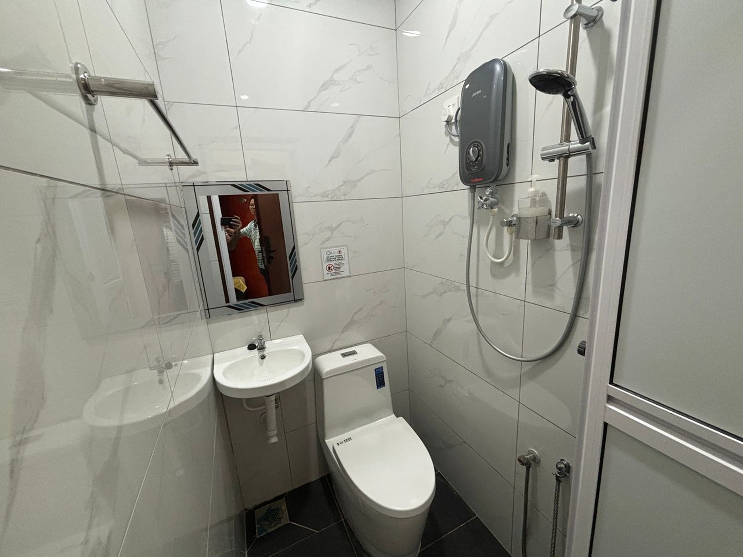 Une salle de bain moderne équipée de toilettes, de deux lavabos, d’un miroir et d’une douche.