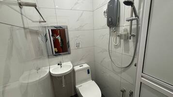 Une salle de bain moderne équipée de toilettes, de deux lavabos, d’un miroir et d’une douche.