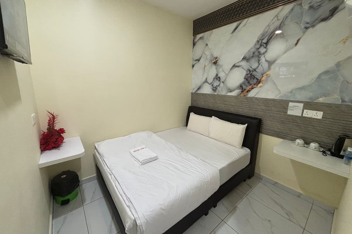 Habitación de hotel con cama, un escritorio pequeño, espejo y pared de mármol.
