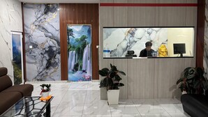 Una moderna zona de recepción con pared de mármol, mostrador de recepción, sofá y mesa de centro.