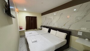 Habitación de hotel con una cama grande, televisión, mesita de noche pequeña, espejo y pared de mármol.