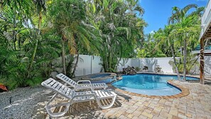 Ein Garten mit Schwimmbad, Liegestühlen und tropischer Bepflanzung.