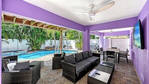 A covered outdoor area with a pool, seating, and a ceiling fan. - Casa Morado | Luxury Holmes Beach Retreat with Heated Pool and Hot tub, Steps to Beach  I .PET FRIENDLY. ANNA MARIA ISLAND! (Holmes Beach)