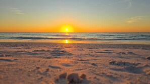 Ein Strand mit untergehendem Sonnenuntergang über dem Meer, der eine ruhige und friedliche Atmosphäre schafft.
