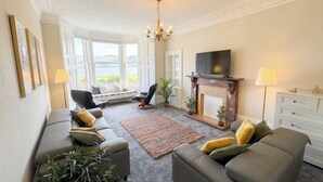 A living room with a fireplace, a TV, and a view of the outdoors. - Stylish River View Stay Sleeps 6 (Dundee)