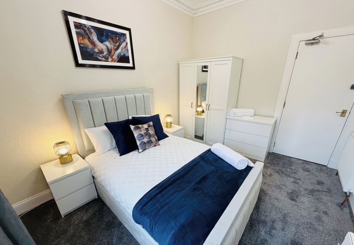 A neatly arranged bedroom with a bed, bedside tables, a wardrobe, and a door.