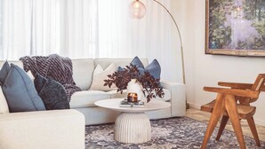 A living room with a sofa, coffee table, and a painting on the wall.