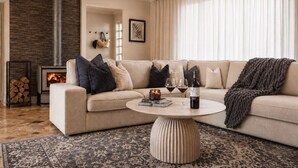 A living room with a beige sofa, a round coffee table, a fireplace, and a patterned rug.