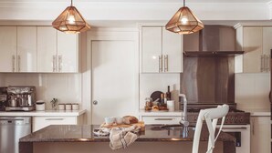 A modern kitchen with white cabinets, a granite countertop, a built-in stove, and pendant lighting.