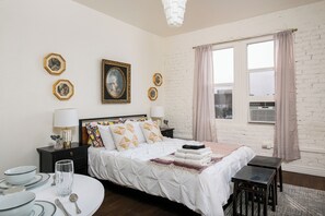A hotel room with a bed, bedside tables, a round dining table, and a large window with curtains. - Amazing studio with AC in vibrant Los Angeles (Los Angeles)