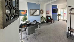 A spacious living area with a dining table, chairs, a sofa, and a TV.