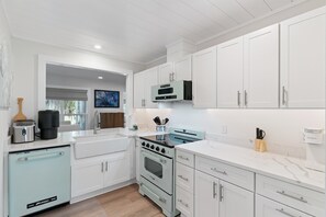 A modern kitchen with white cabinetry, a built-in oven, a microwave, and a dishwasher. - Tranquility At Deer Run (St. Simons Island)