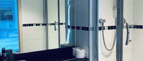 Un baño moderno con ducha envuelta en vidrio, lavamanos blanco y un inodoro.