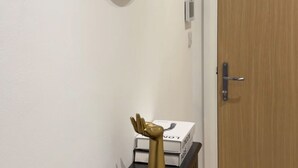 Ein Flur mit einer Holztür, einem schwarzen Konsolentisch und einem goldenen Dekorationsgegenstand sowie einem ovalen Spiegel an der Wand.
