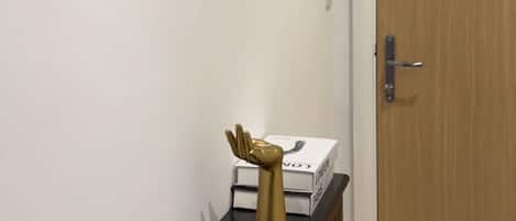 Ein Flur mit einer Holztür, einem schwarzen Konsolentisch und einem goldenen Dekorationsgegenstand sowie einem ovalen Spiegel an der Wand.
