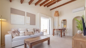 Uma sala de estar com sofá, mesa de centro e área de refeições com cadeiras e mesa.