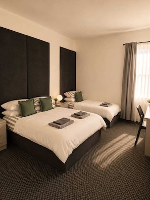 Ein Hotelzimmer mit zwei Betten, einem Schreibtisch und einem Stuhl.