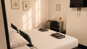 A hotel room with a bed, a desk, a chair, a television, and framed pictures on the wall. - Contemporary Double Room with Private Bathroom (Liverpool)