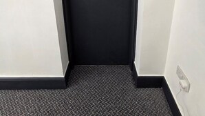 A black door with a push button lock, a carpeted floor, and a wall-mounted emergency exit sign. - Contemporary Double Room with Private Bathroom (Liverpool)