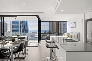 Eine moderne Küche mit Blick auf die Stadt, ein Essbereich mit Tisch und Stühlen sowie eine Bar mit Hockern.