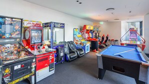 Een kamer met spelautomaten, een pooltafel en comfortabele zitplaatsen.