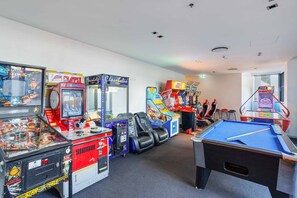 Ein Raum mit Spielautomaten, einem Billardtisch und bequemen Sitzgelegenheiten.