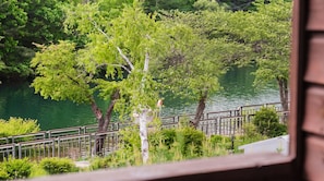 Vista de um rio, com árvores e um guarda-corpo de metal.